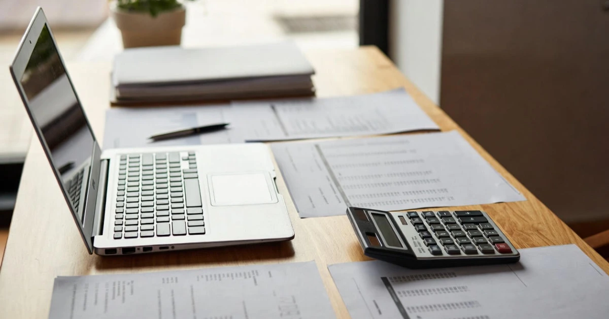 Laptop and invoices on a desk showing ritenuta d’acconto Italy calculation